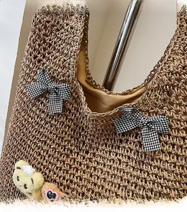 Détail du sac cabas en paille avec nœuds décoratifs et porte-clés ours en peluche