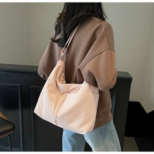 Macro shot of large capacity peach pink quilted nylon tote bag worn over the shoulder