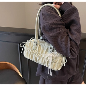 Detail of light green pleated handbag with pearl lace bow charm on shoulder strap