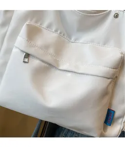 Macro view of white canvas bag showing front flap pocket, metal zipper and brand label