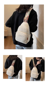 Detail view of cream nylon sling bag featuring a vibrant floral patterned wide strap