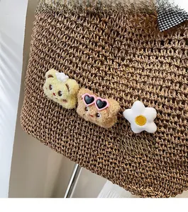 Détail d'un sac cabas en paille tressée avec oursons en peluche et nœud à carreaux