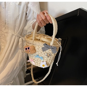 Détail du sac seau en paille avec ours en peluche, nœuds et cordon de serrage