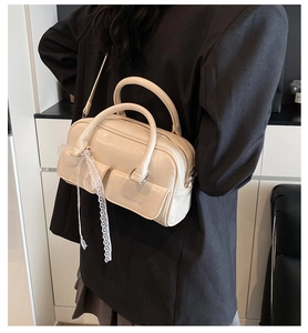 Detail of off-white Boston bag with lace ribbon, shown on model in black suit