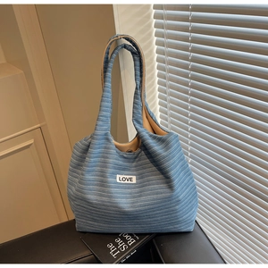 Detailopname van de blauw-wit gestreepte canvas tas met opgenaaide LOVE-patch