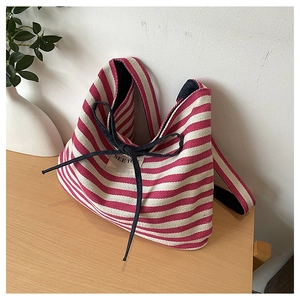 Detail of canvas tote bag featuring pink and white stripes with a small bow and textile tag