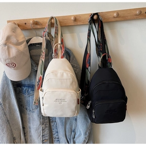 Close-up of nylon chest bags with floral straps hanging in a casual lifestyle setting