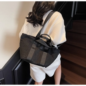 Détail du sac cabas en toile noire avec poignées robustes et large bandoulière confort