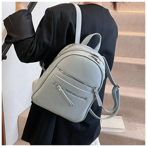 Detail of light blue faux leather backpack showing multi-layer zippers on black suit model