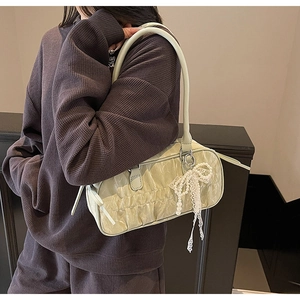 Pale green pleated bowling bag with pearl bow charm shown on model in a casual outfit