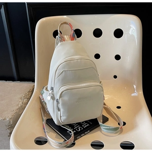 Close-up of cream nylon mini backpack featuring colorful ethnic style webbing straps