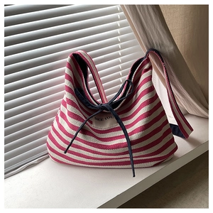 Detail of red striped canvas tote with 'SEE YOU' patch and navy bow tie accent