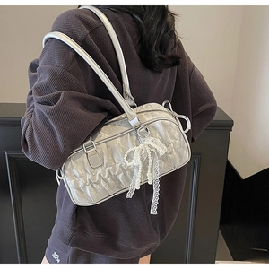 Detail of silver pleated shoulder bag featuring a pearl lace bow charm on waffle sweatshirt