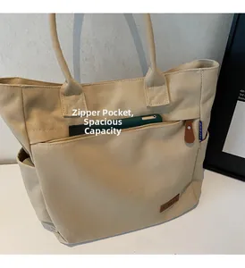 Detailed view of the front zipper pocket on a beige canvas tote with a green mobile phone