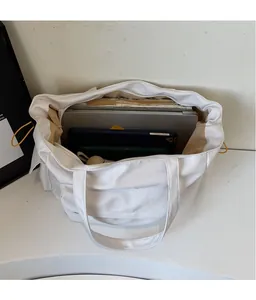 Detailed view showing large capacity of the white canvas tote bag with laptop and books