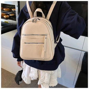 Detail view of stylish cream-colored pebbled leather backpack with silver zippers