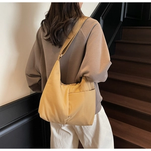 Detail of a ginger yellow nylon hobo tote bag with wide strap on a model