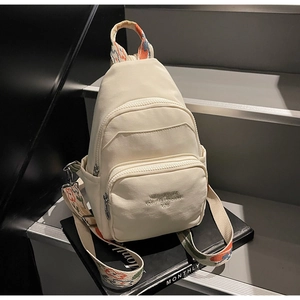Detail of cream canvas chest bag featuring colorful ethnic embroidery strap and embroidery