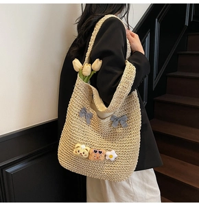 Détail du sac cabas en paille tissé main avec nœuds à carreaux et breloques peluches