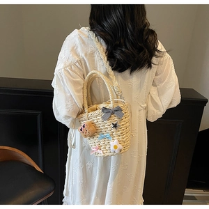 Détail du sac seau en paille tissé main beige avec fleurs et nœuds en ruban
