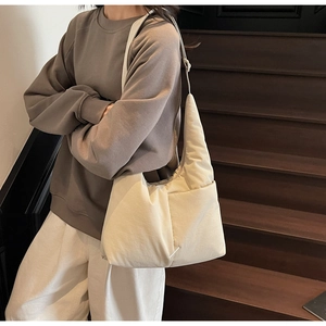 Detail of a creamy white nylon tote bag showing soft texture and side pocket on a model