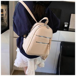 Detail view of beige lychee grain leather backpack with silver zippers and side pockets