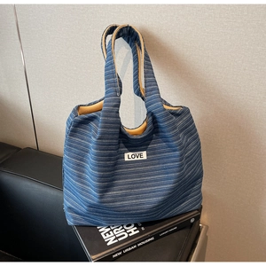 Detail van blauw gestreepte canvas shopper met LOVE-label en gele binnenvoering