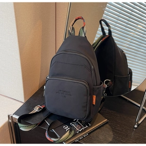 Detail of black nylon mini backpack showing colorful woven straps and side mirror reflection