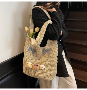 Détail du sac cabas en paille tressée avec breloques d'ours et nœuds à carreaux