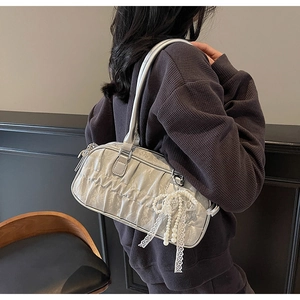Silver metallic pleated shoulder bag with pearl and lace bow charm detail shown on model