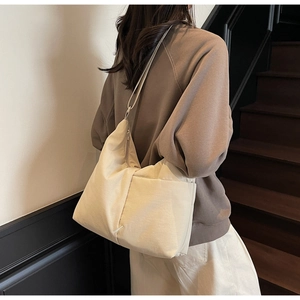 Detailed side view of beige nylon tote bag with functional pocket and zipper closure