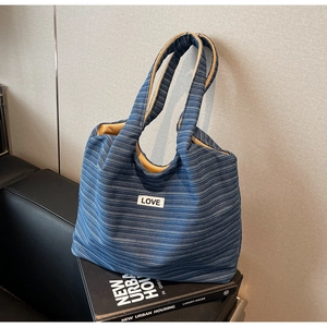 Detail van blauw gestreepte canvas shopper met LOVE-patch en mosterdgele voering