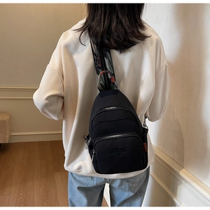 Rear view of black nylon chest bag with ethnic jacquard strap on a model indoors