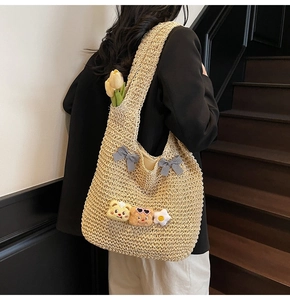 Détail du sac cabas en paille tissée avec nœuds à carreaux et breloques en peluche