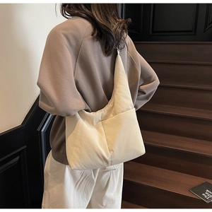 Detail of a beige nylon tote bag showing soft fabric texture and large side pocket