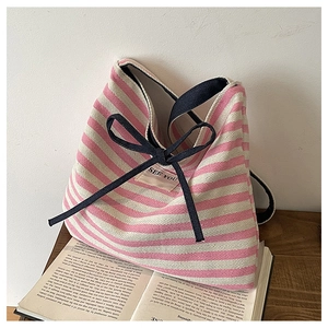 Detail of pink striped canvas tote bag featuring a dark ribbon bow and SEE YOU patch