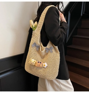 Détail du sac cabas en paille tissée avec nœuds et écussons cartoon sur le mannequin