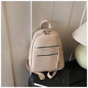 Detailed view of beige pebble grain texture and dual silver zipper pockets on backpack