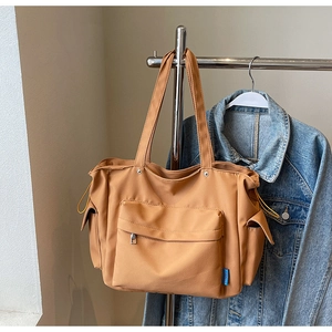 Close-up of yellow canvas tote bag with multi-pocket design on a denim jacket
