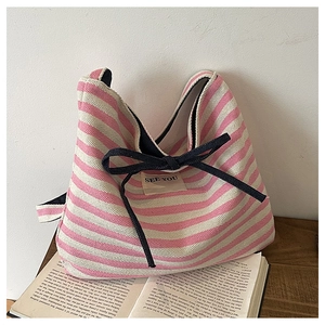 Detailed close-up of pink striped canvas tote bag with blue bow and see you label tag