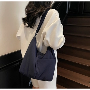 Navy nylon tote bag featuring adjustable wide strap and side pocket on a model