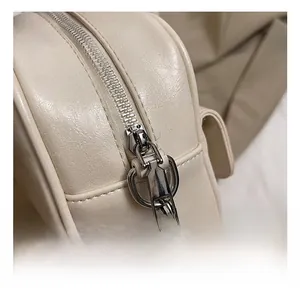 Close-up of the silver metal zipper and hardware details on the beige travel bag
