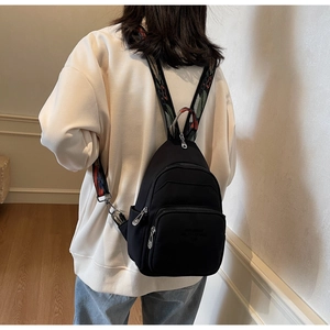 Detail of black nylon sling bag with colorful ethnic pattern jacquard strap on model
