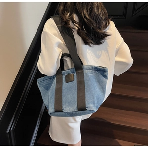 Vue de dos d'un mannequin portant un grand sac cabas en jean bleu sur un escalier