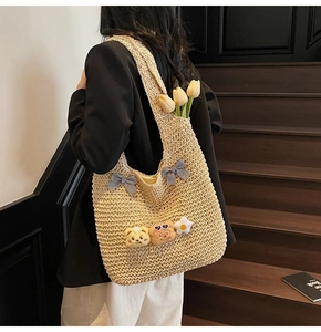Détail du sac cabas en paille beige avec nœuds à carreaux et breloques mignonnes