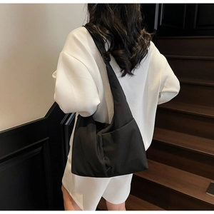 Chic black nylon hobo tote bag shown worn as a crossbody on a stylish commuter