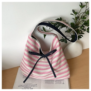 Close-up of pink and white striped canvas tote bag with a black ribbon bow on a wooden desk