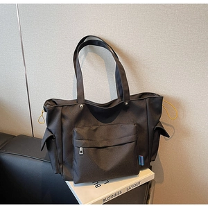 Close-up of black canvas tote bag with large front zipper pocket and yellow drawstring details