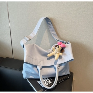 Detalle del bolso tote de cuero azul claro con textura de lichi y un tierno colgante de perro