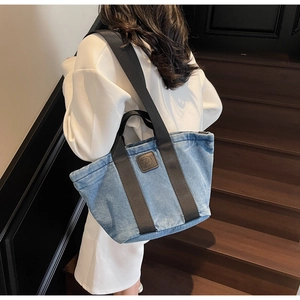 Détail du cabas en denim bleu clair avec logo en cuir et poignées tissées